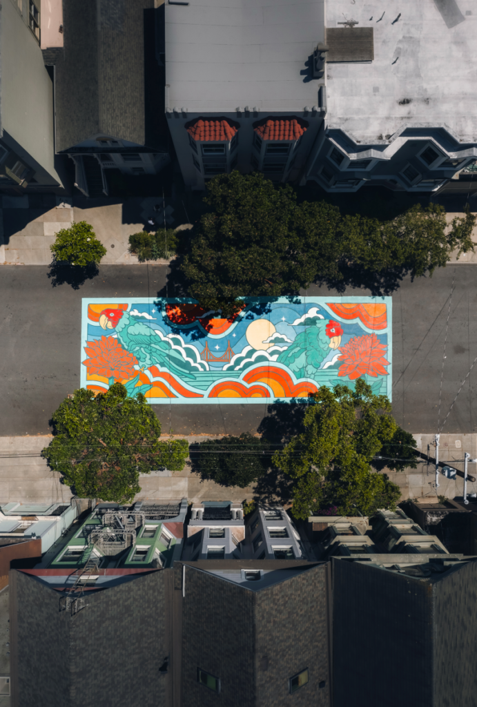 Aerial view of a vibrant mural by Matley Hurd featuring flowing teal, orange, and red waves with a bright yellow sun, painted on a Lyon Street in San Francisco.